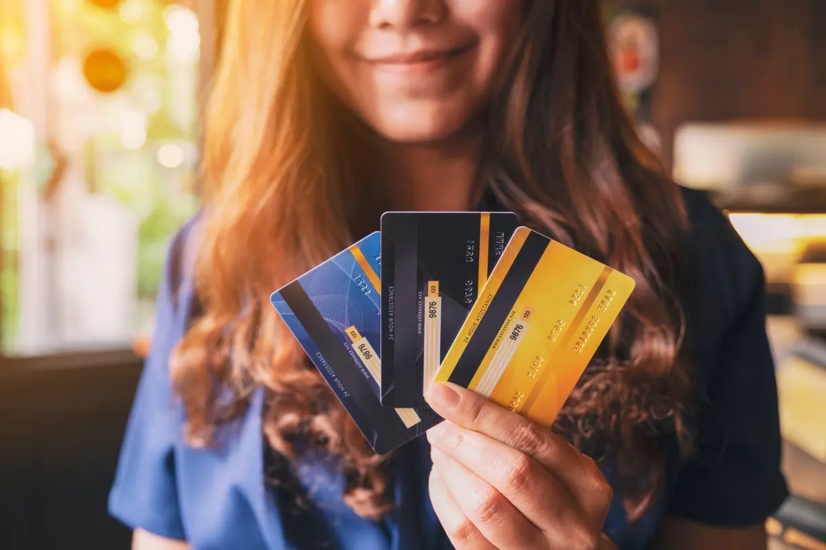 Femme souriante montrant plusieurs cartes bancaires