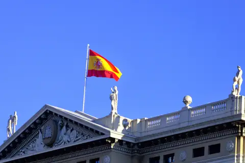 Drapeau espagnol flottant au sommet d'un bâtiment officiel orné de statues