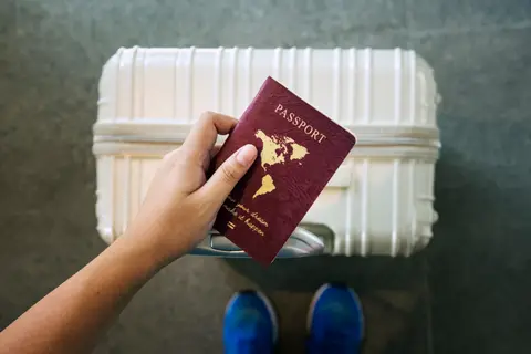 Main tenant un passeport au-dessus d'une valise blanche prête pour le départ