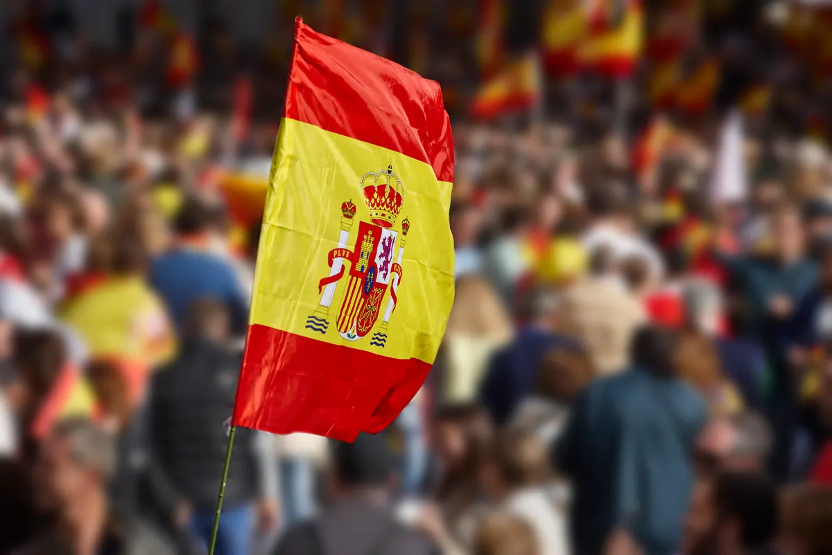 Drapeau espagnol brandi au-dessus d'une foule rassemblée pour une célébration
