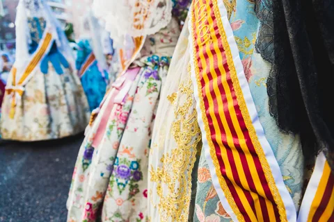 Robes traditionnelles brodées et écharpes rouge et jaune portées lors d'un défilé de fête populaire