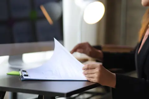 Personne feuilletant des documents administratifs à un bureau