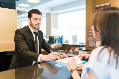 Conseiller bancaire présentant des documents à une cliente au guichet d'une agence