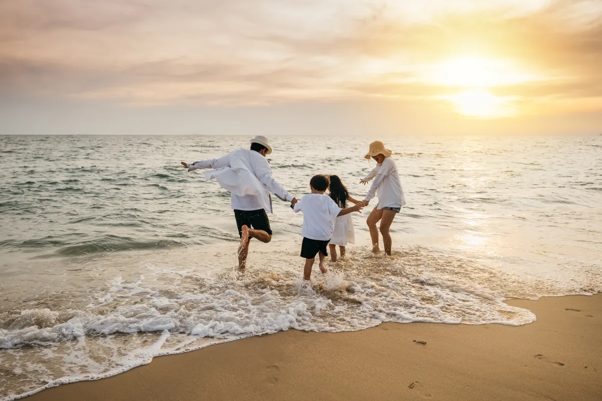 Famille jouant dans les vagues sur une plage au coucher du soleil