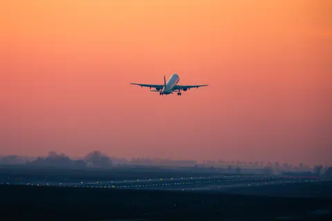 Avion qui décolle au coucher du soleil au-dessus d'une piste d'aéroport