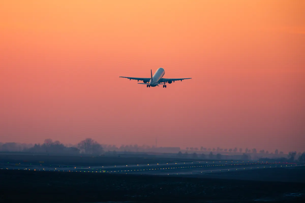 Avion qui décolle au coucher du soleil au-dessus d'une piste d'aéroport