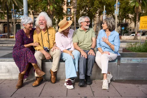 Groupe de retraités souriants assis sur un banc dans une rue de centre-ville